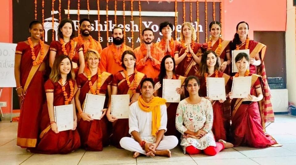 Photo de groupe de la promotion de l’école Rishikesh Yogpeeth, diplômes en main, en tenues traditionnelles